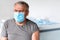 Elderly man in a medical office getting ready for vaccination. Portrait of senior man wearing medical mask for Covid -19 Flu