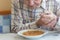 Elderly man with Parkinsons disease holds spoon in both hands