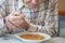 Elderly man with Parkinsons disease holds spoon in both hands