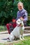 Elderly Man is Petting a White Pitbull Terrier Dog in the Park