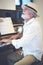 An elderly man plays the piano at home happily