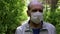 An elderly man in a protective mask walks in the Park, a walk in the fresh air after quarantine, a precautionary measure