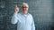 Elderly man raising finger and smiling having good idea in class with chalkboard