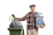 Elderly man with a recycling bin throwing a garbage bag in a trash can