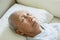 Elderly man resting in bed with eyes closed