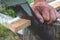 An elderly man is sawing a board with an old hand saw. Only part of the saw and the hand are in the close-up shot