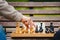 Elderly man senior holds chess piece game board outdoors