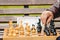 Elderly man senior holds chess piece game board outdoors