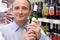 Elderly man in shop with wine bottle