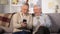 Elderly man showing funny photo on smartphone aged friend, having fun at home