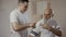 Elderly man shows a pain place on shoulder to masseur