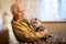 elderly man sits on a bed with a scottish fold cat in his arms