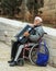 An elderly man sits on a wheelchair and holds an accordion in his hands in the old city of Nazareth in Israel