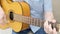 Elderly man sitting on a chair and playing guitar. Man plays the acoustic guitar