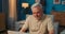 Elderly man sitting at desk with laptop in the evening. Senior works in a salon.