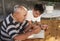 A elderly man sitting doing crosswords hobby with his grandson