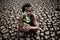 An elderly man sitting with dry soil and cracked in a hand held seedling,global warming