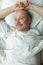 An elderly man slyly lies on the bed smiling.