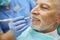 Elderly man smiling while having his teeth polished