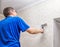 Elderly man smoothing the wallpaper with a roller