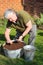 Elderly man sowing seeds in container.