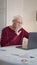 An elderly man starts a call via the Internet. He greets the interlocutor by waving his hand