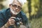 Elderly man takes pictures of flowers in park, pensioner on walk. Active hobby of mature person