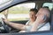 Elderly man on telephone while driving wife in passenger seat