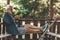 An elderly man is typing a message on the phone while relaxing on a bench. Active lifestyle in old age. Spending time in the fresh