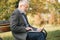 Elderly man use laptop in the park. Handsome senior man in glasses work outside