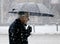 Elderly man walking alone under umbrella snowy city street in heavy snowfall