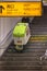 Elderly man walking down a staircase with a trolley used for garbage collection in a train station.