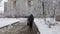 An elderly man walks with a package in his hands on the sidewalk in the winter season