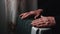 An elderly man warms his hands over an electric heater