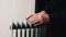 An elderly man warms his hands over an electric heater