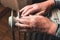 An elderly man warms his hands over an electric heater. In the off-season, central heating is delayed, so people have to buy