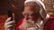An elderly man with a white beard listens to music in a Santa Claus costume on Christmas eve. Santa Claus in the new