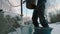 An elderly man in the winter in the village draws water from a well and pours it into buckets.