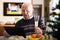 Elderly man wishes Merry Christmas by laptop to friends and acquaintances sitting at the festive table in house