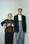 Elderly man and woman in art performance, replica of painting american gothic. Retro style, comparison of eras and