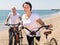 Elderly man with woman in white shirts walking with bicycles on