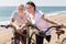 Elderly man with woman in white shirts walking with bicycles on