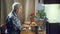 Elderly man working on a laptop and making notes in a notebook while sitting at a table at home