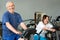 Elderly man working out on exercise bike in gym.