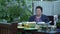 Elderly mature woman sits at dining table in courtyard. Portrait of senior retired woman sitting at table at summer house. Family