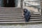 An elderly monk with a staff sits on the steps of the temple and asks for alms. Prayer of healing and alms.