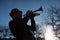 An elderly musician plays in the street on a trumpet