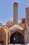 Elderly Muslim enters in clay building with minaret, Yazd, Iran.