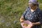 Elderly Muslim woman holding a small pink wash tub of fresh potatos by hand after spring rain