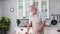 elderly old man pouring clean clear water from a pitcher into a glass to quench his thirst in the kitchen